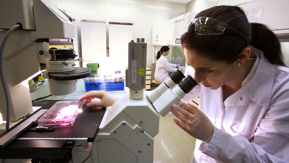 Cientifica mirando por un microscopio