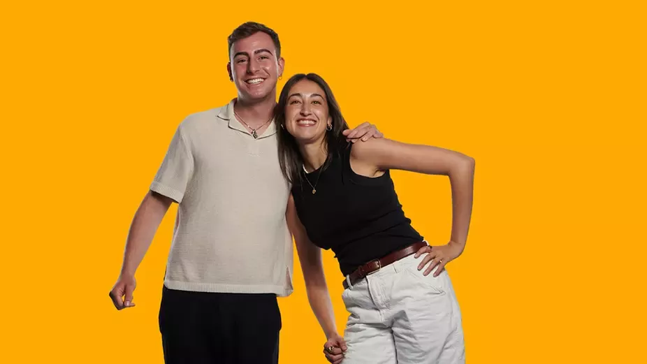 Dos jóvenes posando juntos sobre fondo amarillo para una campaña de empleo y desarrollo profesional