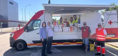 Representantes de Cruz Roja y Nestlé posan junto a un vehículo de reparto con cajas de producto donadas
