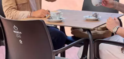 Personas tomando café en una terraza con sillas fabricadas a partir de cápsulas usadas y posos de café.