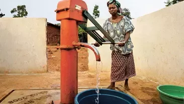 Mujer extrayendo agua de un pozo