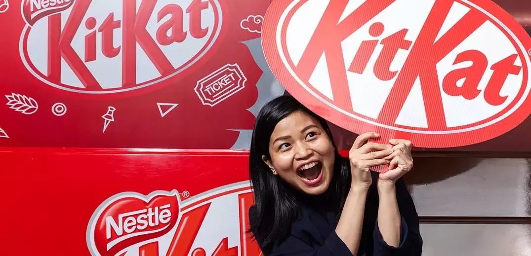Trabajadora de Nestlé sujetando un logo de Kit Kat